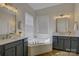 This bathroom features a dual sink vanity, a large soaking tub, and a bright window with blinds at 9810 Daufuskie Dr, Charlotte, NC 28278