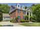 A brick two-story home with blue shutters, dormer windows and a driveway, surrounded by green trees and landscaping at 9810 Daufuskie Dr, Charlotte, NC 28278