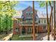 Back exterior view of a two-story brick home featuring a large deck and backyard at 9810 Daufuskie Dr, Charlotte, NC 28278