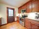 Well-lit kitchen with wooden cabinets, granite countertops, and stainless steel appliances near the back door at 110 Dutch Creek Rd, Rockwell, NC 28138
