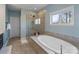 Bright bathroom features a soaking tub, glass shower, and neutral tile at 14010 Promenade Dr, Huntersville, NC 28078