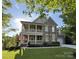 Charming two-story home featuring a stone facade, double porches, lush lawn, and attached garage at 14010 Promenade Dr, Huntersville, NC 28078
