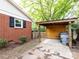 Backyard showing the brick house, an open wood shed, and trash bins at 1408 Wicker Dr, Charlotte, NC 28210