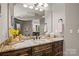 Bathroom vanity featuring granite counters, wood cabinets, and a large mirror with decorative lighting at 14130 Lea Point Ct, Huntersville, NC 28078