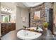 Stone-accented bathtub with wooden tray offers a spa-like experience in this modern bathroom at 14130 Lea Point Ct, Huntersville, NC 28078