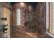 Walk-in shower featuring dark tile walls, multiple shower heads, and a built-in bench at 14130 Lea Point Ct, Huntersville, NC 28078