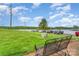 Iron bench on grassy lawn overlooking parking area and lake with bridge in the distance at 1424 River Dr, Belmont, NC 28012