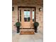Close-up of an elegant front door with glass panes, flanked by topiary and a welcome mat at 15906 Youngblood Rd, Charlotte, NC 28278