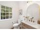 Cozy powder room features brushed gold fixtures, elegant vanity, and natural light from the window at 15906 Youngblood Rd, Charlotte, NC 28278