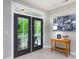 Double doors to a deck from a bright room with neutral walls, with a wooden table, lamp and city art on the wall at 19034 Cypress Garden Dr, Davidson, NC 28036