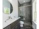 Modern bathroom featuring a glass shower, gray tile and a round mirror above the vanity at 2008 Plain Field Dr, Bessemer City, NC 28016