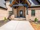 Inviting covered front porch with brick columns, a stylish black front door, and well-maintained landscaping at 2008 Plain Field Dr, Bessemer City, NC 28016