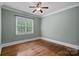 Bedroom features hardwood floors, neutral paint, and natural light from a window at 208 Grasshopper Cir, Mooresville, NC 28117