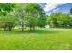 Wide shot of the backyard shows a gentle slope and mature trees surrounding the property at 220 Tomberlin Rd, Mount Holly, NC 28120