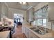 Galley kitchen featuring double sinks, vintage floral curtains, and access to the back porch at 220 Tomberlin Rd, Mount Holly, NC 28120