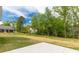 A view of the back of the house with a grassy lawn and wooded border, ready for customization at 2212 University Dr, Lancaster, SC 29720