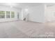Open concept living room features neutral carpeting, large windows, and access to stairs at 24558 Blue Heron Cir # 402, Lancaster, SC 29720