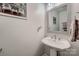 Half bath featuring a pedestal sink, decorative mirror, and neutral wall color at 308 Valhalla Dr, Harrisburg, NC 28075