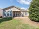 Back yard view reveals the home's back elevation, well-maintained lawn and covered patio at 43014 Mimosa Ct, Indian Land, SC 29707