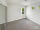 Carpeted bedroom with three windows and a sliding mirror door closet at 4437 Devonhill Ln, Charlotte, NC 28269