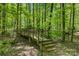 Wooden foot bridge with brick supports leading through a wooded area at 4516 Stryker Dr, Matthews, NC 28104