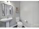 Stylish half bathroom with pedestal sink, framed mirror, and neutral color palette at 5025 Willing Ct, Fort Mill, SC 29707