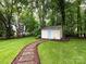 Landscaped backyard featuring a storage shed, a stone walkway and lush green grass at 5621 Landale Ct, Concord, NC 28027