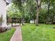 Beautiful backyard featuring a pergola, lush landscaping, and a storage shed at 5621 Landale Ct, Concord, NC 28027