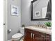 Modern bathroom featuring a vanity with granite countertop, toilet, and a decorative mirror at 575 Marthas View Nw Dr, Huntersville, NC 28078