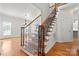 Elegant staircase with hardwood steps, carpet runner, and decorative iron railing, adding architectural interest to the home at 6201 Creola Rd, Charlotte, NC 28270