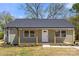 Inviting home featuring a covered porch with wood columns, green siding and a modern white front door at 6525 Kershaw Camden Hwy, Heath Springs, SC 29058