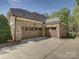 Stone home with a large driveway leading to a three-car garage with brown doors and brown trim at 712 Chase Ct, Fort Mill, SC 29708