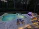 Backyard at dusk featuring a luxury pool, spa, stone patio, lounge chairs, and lush landscaping at 712 Chase Ct, Fort Mill, SC 29708