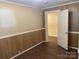 Cozy bedroom with paneled walls and hardwood floors with a view into another room through an open doorway at 8350 Nc Hwy 90 E Hwy, Stony Point, NC 28678