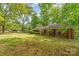 View of a single-story brick home with green lawns, mature trees, and visible 'For Sale' signage at 102 Forest Ct, Huntersville, NC 28078