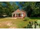 Quaint brick home with a covered porch, set amidst lush greenery and a vibrant blue sky at 119 Washington St, York, SC 29745