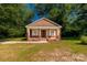 Cozy brick home with a covered front porch surrounded by green trees on a sunny day at 119 Washington St, York, SC 29745