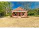 Inviting brick home with a covered front porch surrounded by green trees and a straw-covered yard at 119 Washington St, York, SC 29745