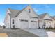 Elegant home featuring a three-car garage, white siding, and black accents against a clear blue sky at 13097 Arnold Palmer Cir # 844, Lancaster, SC 29720