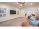 Open living room with plush carpet, mounted TV, ceiling fan, and comfortable leather seating at 13103 Union Square Dr, Huntersville, NC 28078