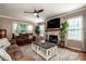 Bright living room featuring a fireplace, mounted TV, ceiling fan, large windows, and comfortable seating with a decorative rug at 145 Meadow Pond Ln, Mooresville, NC 28117