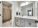 Bright bathroom featuring double sinks, modern fixtures, gray cabinets, and a tile shower at 15312 Ravenall Dr, Huntersville, NC 28078