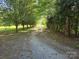 Long gravel driveway lined with a canopy of mature trees leading to a secluded property at 1855 7Th St, Salisbury, NC 28144