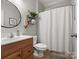 Bathroom features wood vanity, toilet, shower with curtain, and decorative shelves at 2002 Potomac Rd, Indian Trail, NC 28079