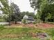 Picturesque view of a two-story home nestled among mature trees, with a charming front porch and well-maintained lawn at 2214 Cannonade Ct, Matthews, NC 28105