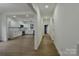 Hallway leading to a modern kitchen, featuring open floor plan, white walls, and wood look flooring at 307 E 2Nd St, Lowell, NC 28098