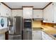 Close up of kitchen features stainless steel appliances, wood trim, and white cabinets at 319 Hatley Ne Cir, Concord, NC 28025