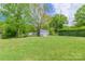 Large backyard with mature trees, an outbuilding, and ample space for outdoor activities at 400 Rhyne St, Stanley, NC 28164