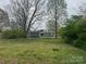 View of backyard with mature trees, chain link fence, shed, and fire pit at 400 Rhyne St, Stanley, NC 28164