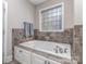 A bathtub with beautiful tiled walls and cabinetry underneath for storing your bathroom essentials at 4008 Widgeon Way, Waxhaw, NC 28173